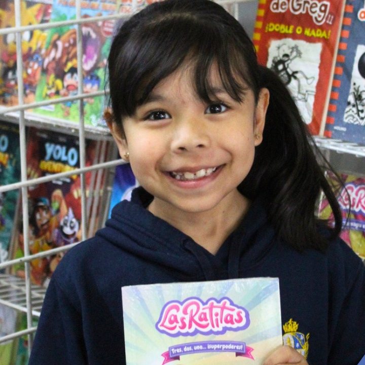 Alumna de Primaria con el libro que escogió en la feria de lectura